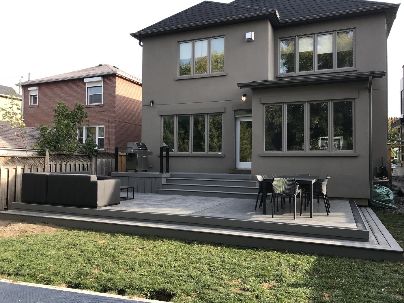 Large composite deck with lounge and dining areas at a modern home