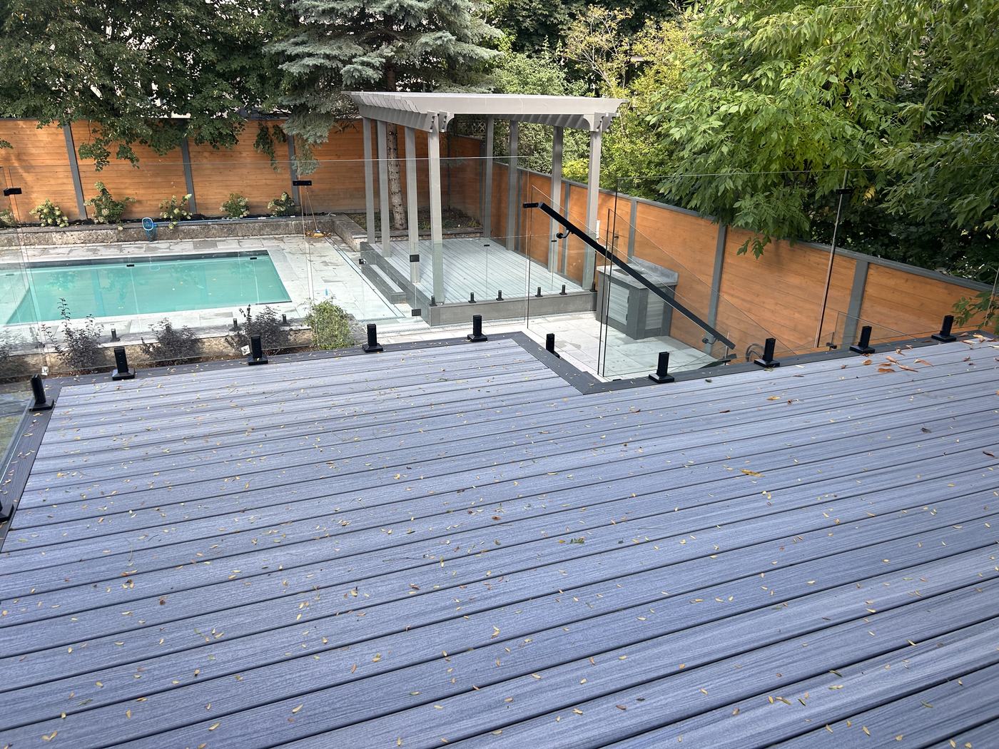 Composite multi-level deck with glass railing, pergola, and pool