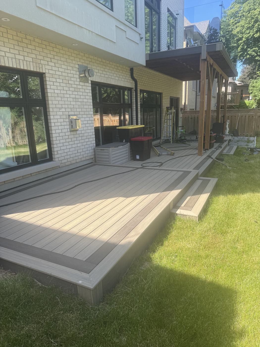 Composite deck with a tall louvered pergola and glass railing
