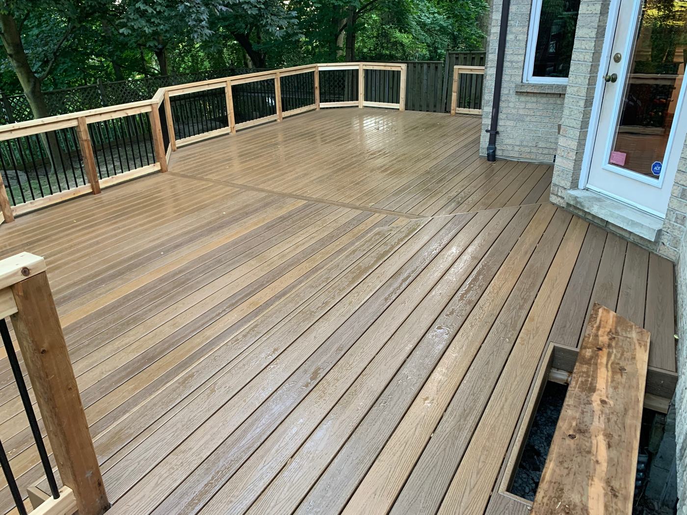 Wide composite deck with glass railing at a modern stone home